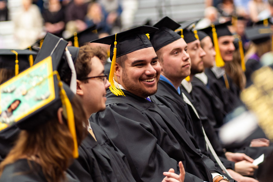 Graduates dressed in caps and gowns smile during the WSU Commencement Ceremony.