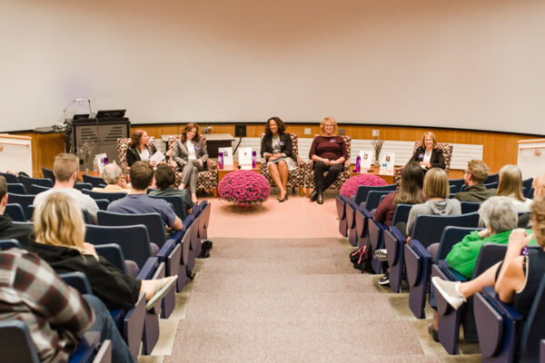 Guest speakers give a lecture to a crowd in an auditorium on campus.