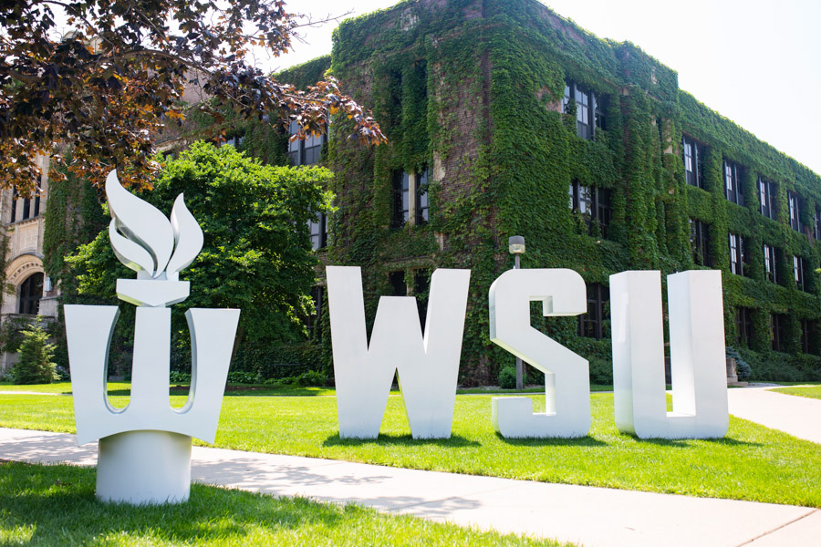 Large metal letters spell "WSU" and show the Flaming W on the lawn in front of Somesen Hall.