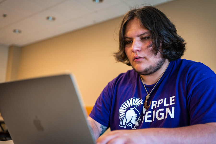 A male WSU student works on a laptop.