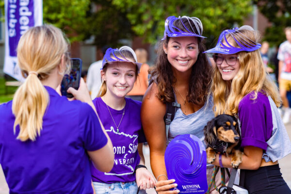 A group of female students decked out in WSU gear pose for a photo during a campus event.