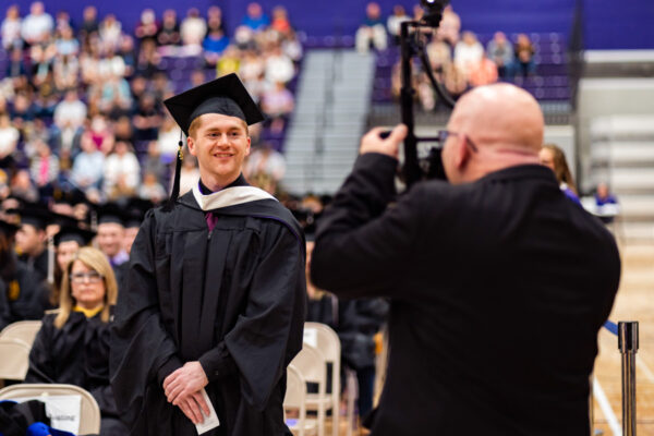 A professional photographer takes a picture of a graduate during the WSU Commencement Ceremony.