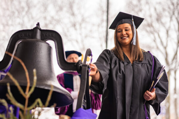 A female graduate happily rings the bell after the WSU Commencement Ceremony.