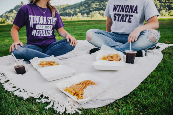 Two students have a picnic in the park by Lake Winona.