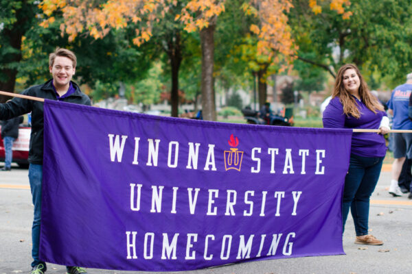 Two students carry a large banner that reads