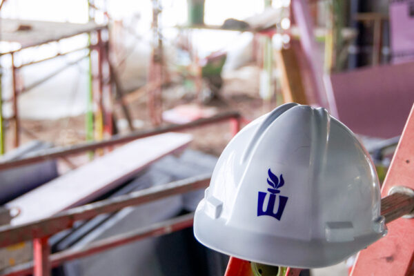 A white hard hat with the flaming W logo rests amid a construction zone on the WSU campus.