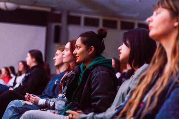 Students sit in an auditorium listening to a speaker.