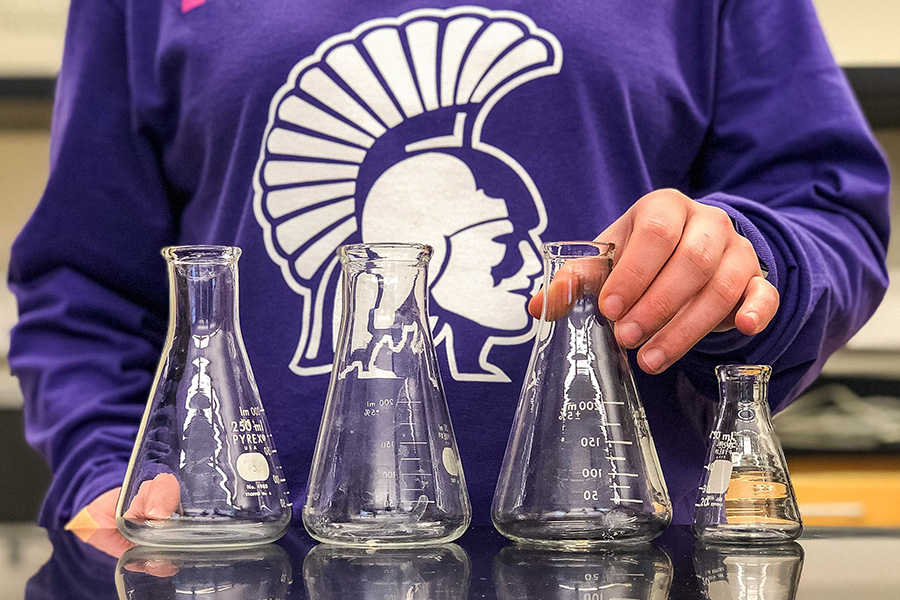 WSU student standing behind chemistry beakers