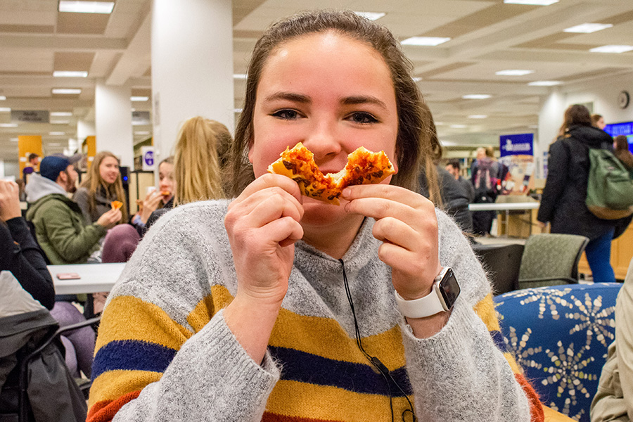 WSU student holding a piece of pizza
