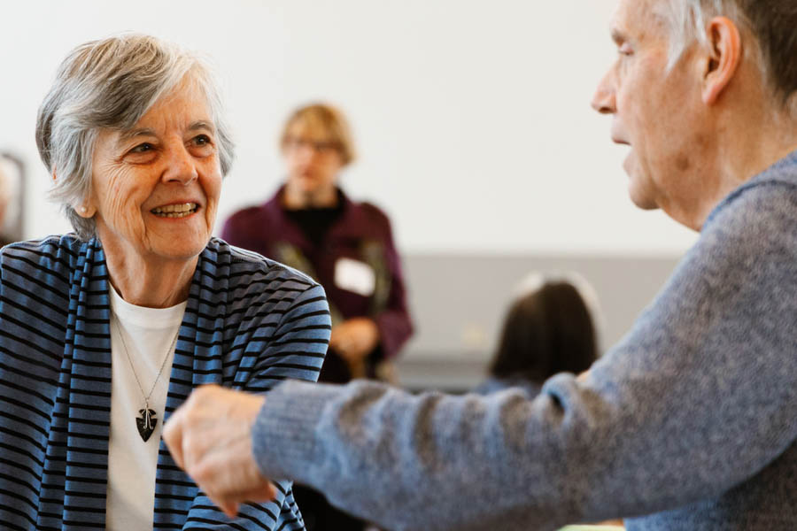 Two older adults smiling and talking to each other.