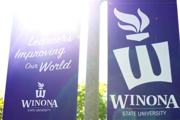 A close view of purple banners with the Winona State flaming W logo and the mission statement 