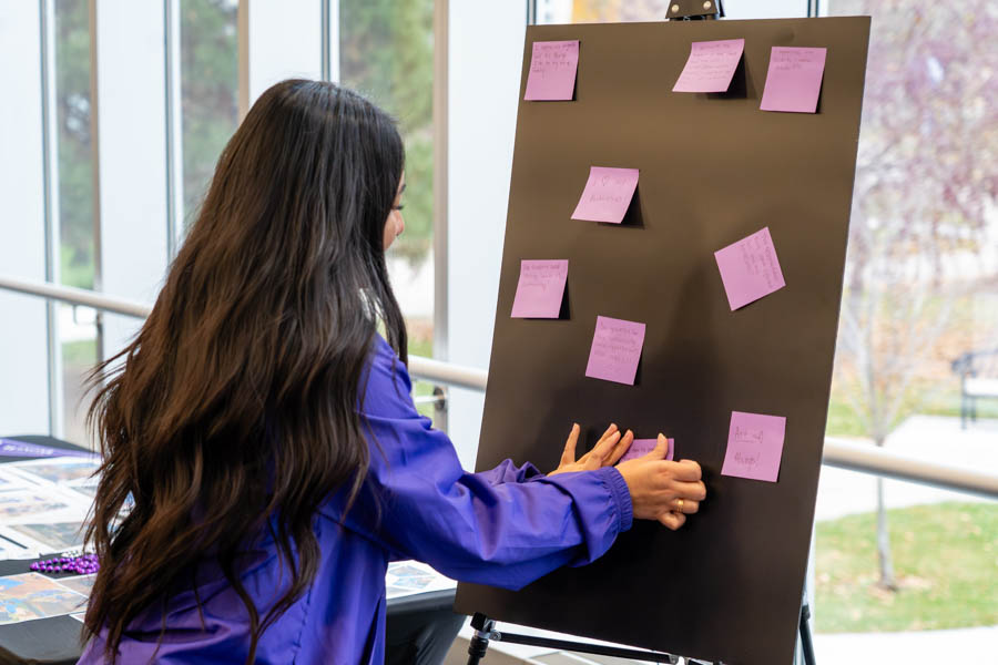 A female student sticking a note to a board.