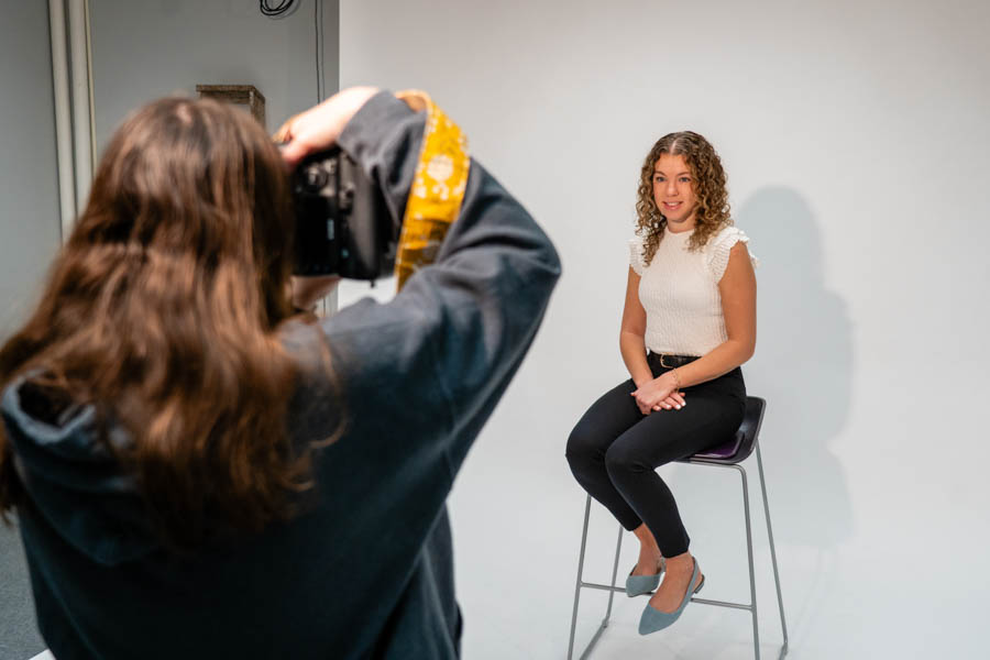 WSU student using a camera to take another student's headshot in the Photo Studio.