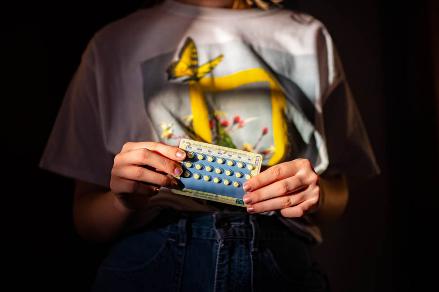 Female student holding birth control pills.