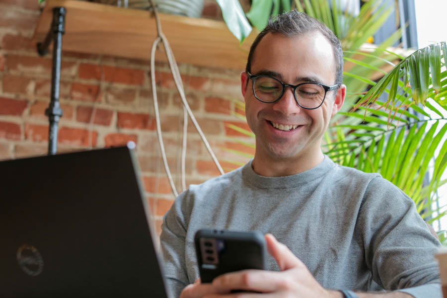 Male student smiling at a cell phone.