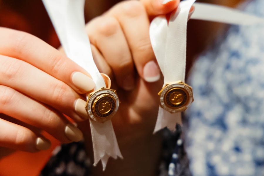 Hands holding pins from a Nursing pinning ceremony