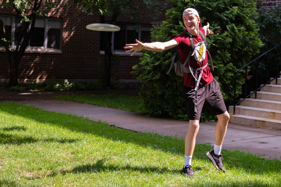 Winona State student throwing a frisbee on campus.