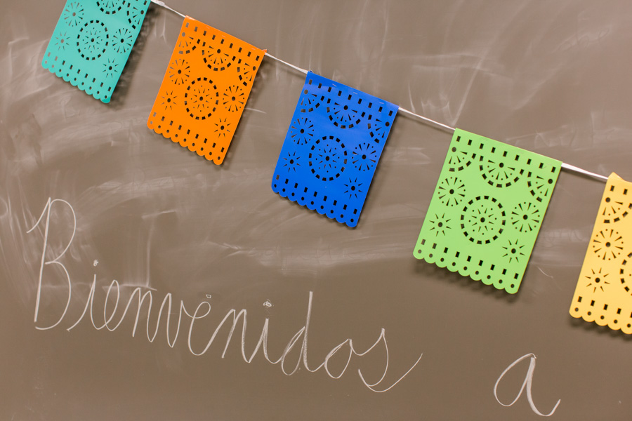 Spanish flags against a chalkboard with Spanish writing.