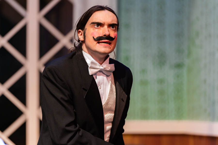 WSU student wearing a tux/suit and a mustache performing on stage.