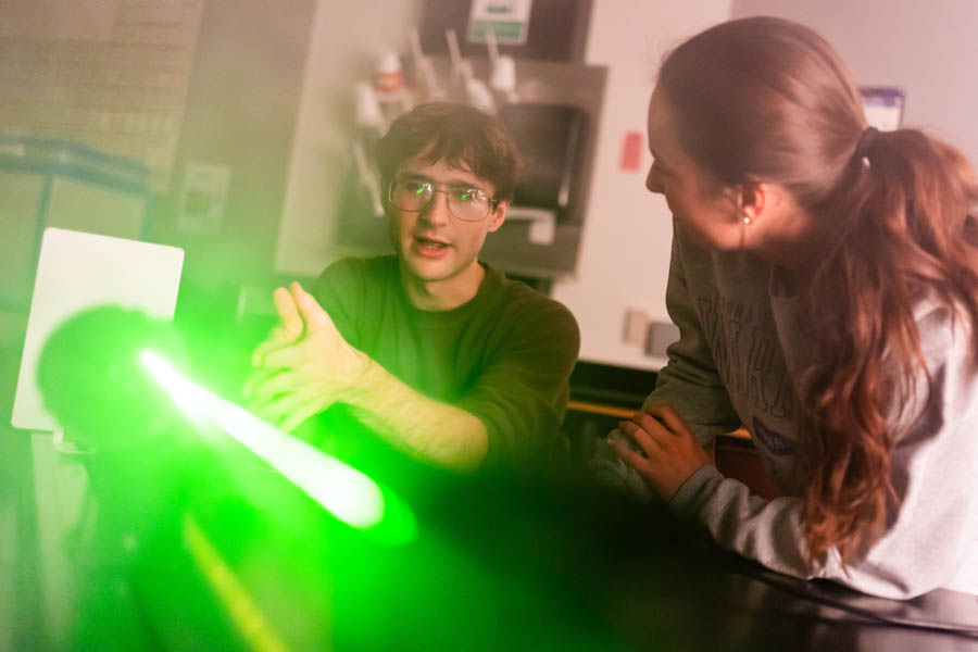 WSU students studying a laser in a science lab.