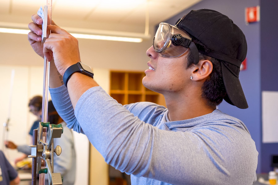 WSU student wearing a hat and using a measurement device.