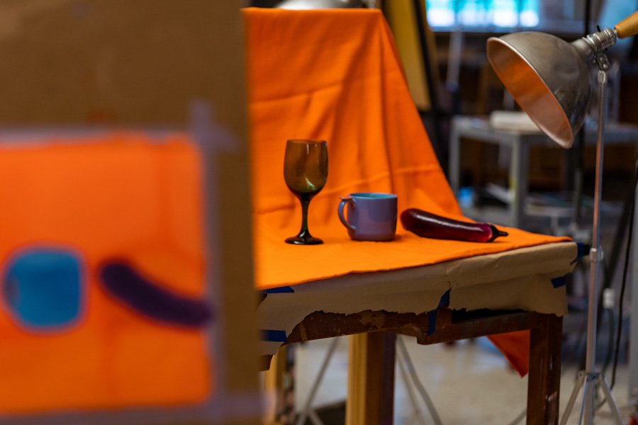 Painting of a still life art setup of three objects on a table with a lamp.