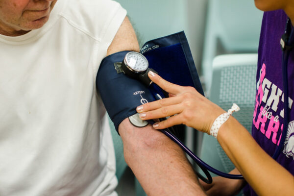 WSU student taking community member's blood pressure.