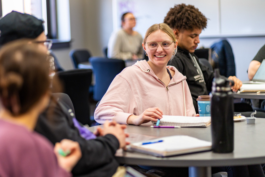 WSU students sitting in a classroom and smiling.