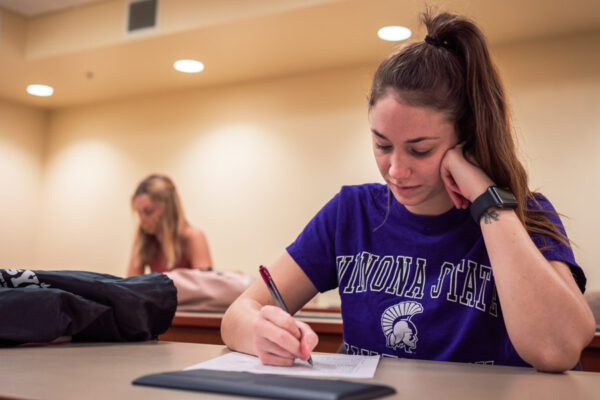 A female student takes notes during class at WSU.