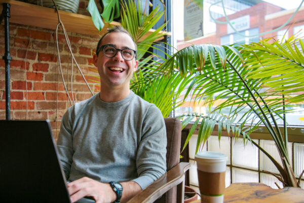 A male student works on a laptop in a coffee shop.