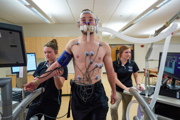 Three students conduct a fitness test with a treadmill in the Exercise Science lab.