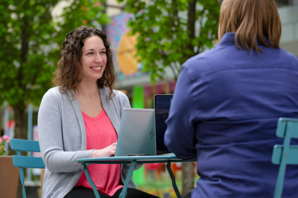 A female student types on a laptop at an outdoor table.