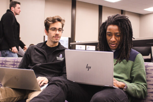 Two male students work on laptops in the Business Engagement Center.