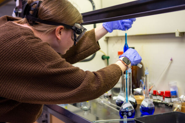 Student wearing goggles conducting a chemical experiment