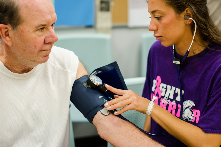 A WSU student takes a blood pressure reading of an older adult.