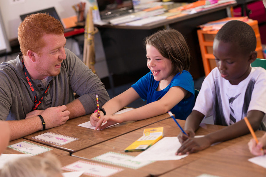 A male WSU student teacher works with two young kids