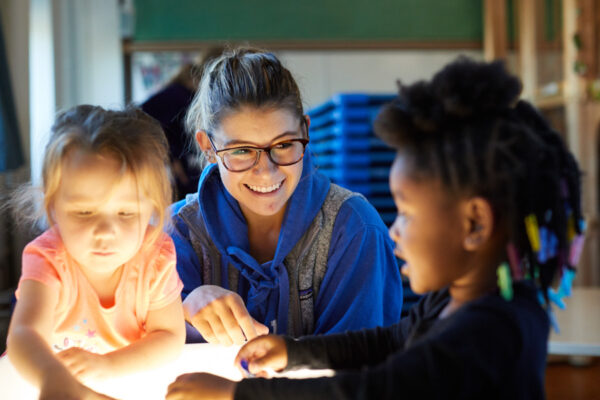 A student works with elementary children in a classroom.