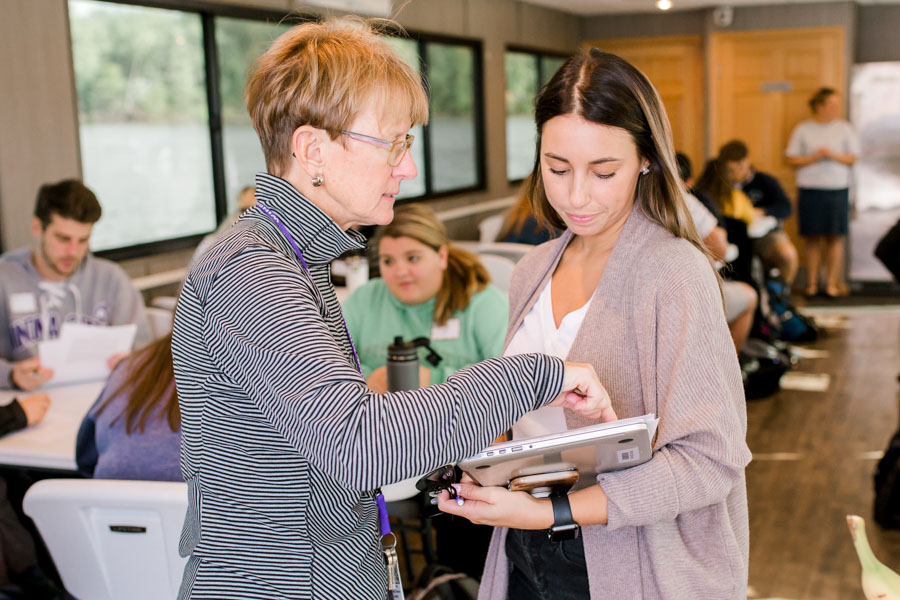 WSU professor speaking with student who holds a laptop.