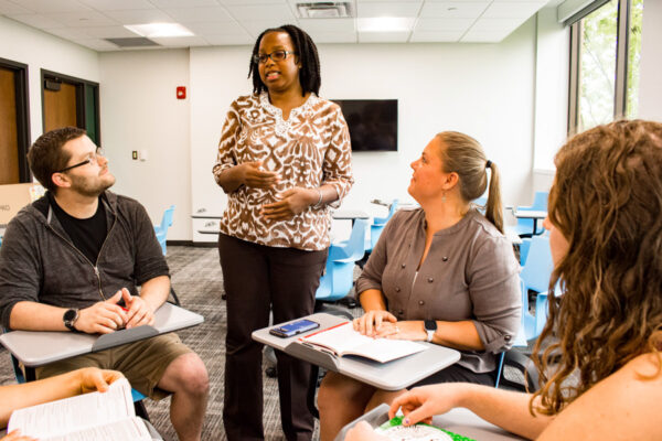 A professor discusses a point with a group of adult students.