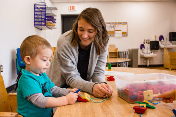 A student teacher plays with a kid with blocks in a classroom.