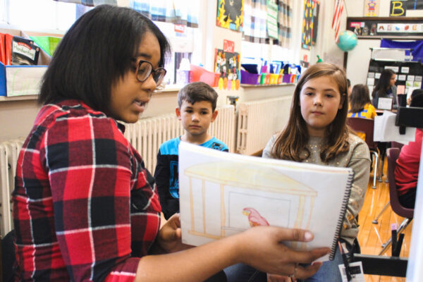 A student teacher reads to kids in a classroom.