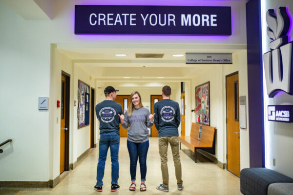 Students pose beneath a sign reading