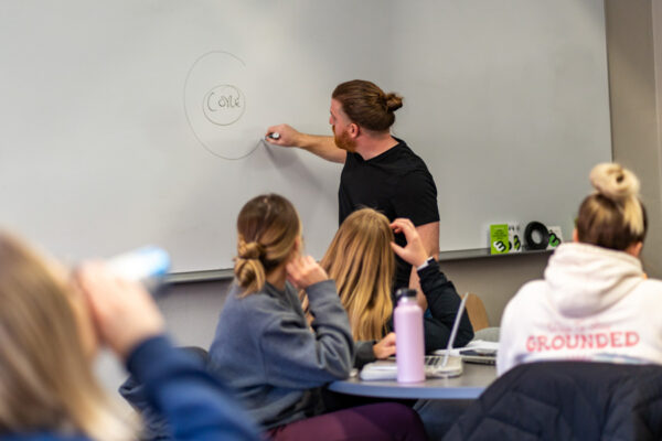 A professor draws a diagram on a whiteboard during class.