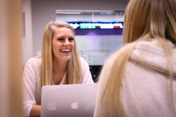 Students chat while working on laptops.