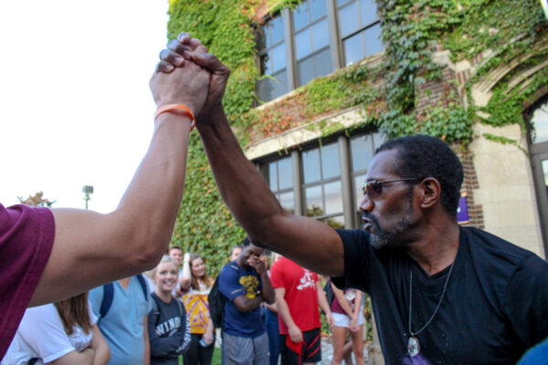 Two people clasp hands above their heads in celebration at a campus event.