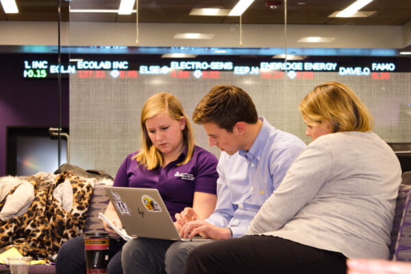 Three students work together on a laptop in the Engagement Center.