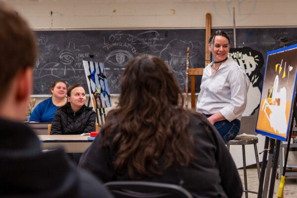 Students discuss an art piece with a professor in a WSU classroom.