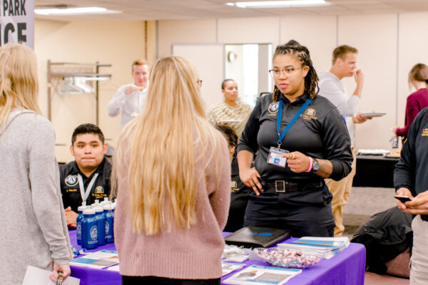 A student talks with a police officer at a table during a WSU Career Fair.