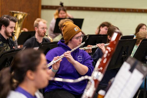 Students play their flutes, bassoons, and brass instruments during a band practice session.
