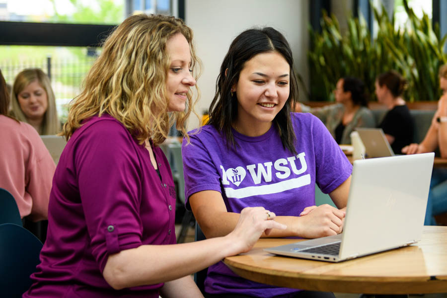 Female students looking at a laptop in a coffee shop.